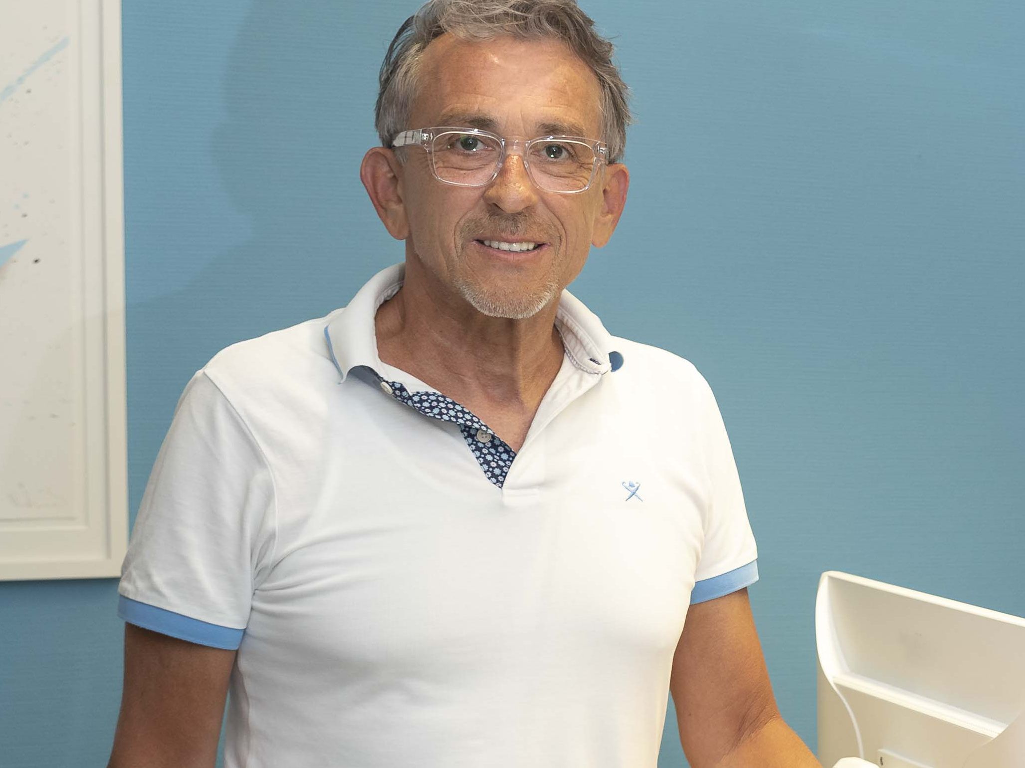 Dr. Frank Conrad ist Urologe und Männerarzt in Köln. Das Bild zeigt ihn lächelnd und zugewandt am Empfang seiner Praxis.